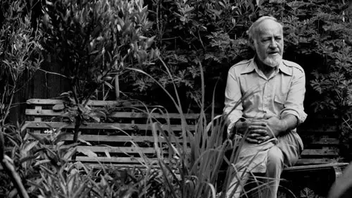 Bill Mollison sitting on park bench surrounded by plants.