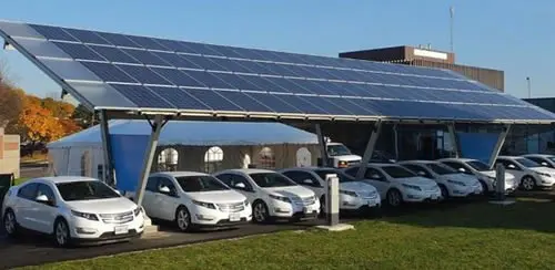 Electric cars charging under solar panel canopy.