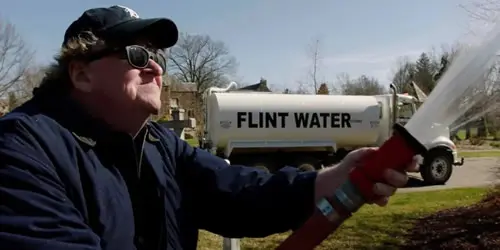 Man spraying water, Flint Water truck behind.