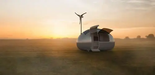 Eco-friendly home with wind turbine at sunrise.