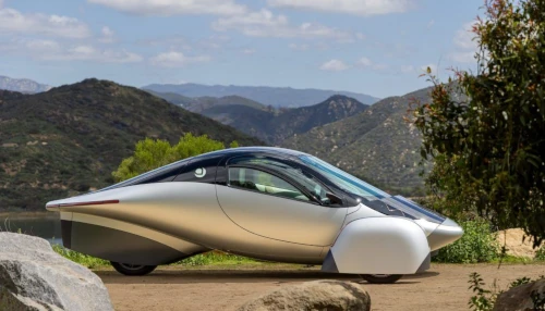 Futuristic car parked with scenic mountain backdrop.