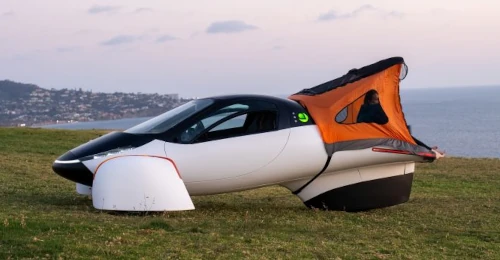 Futuristic solar-powered car with tent attachment outdoors.