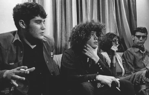 Group of four people sitting and talking indoors.