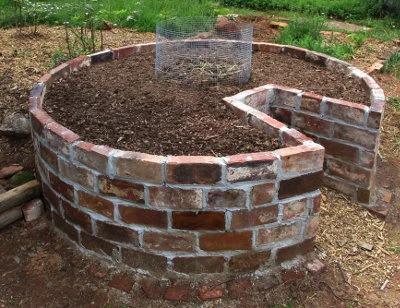 Construcción de un huerto en espiral con ladrillos, tierra y malla metálica.