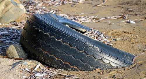 Viejo neumático parcialmente enterrado en la arena.